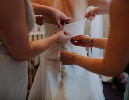 Bride putting on her wedding dress at Bassmead Manor Barn