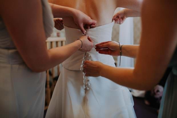 Bride putting on her wedding dress at Bassmead Manor Barn