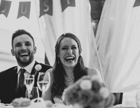Bride and groom laughing during the speeches